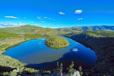 Scenic view of lake and mountains against blue sky