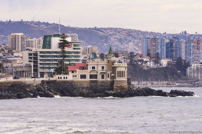 Buildings by sea against sky in city