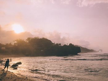 Man at sea against sky during sunset