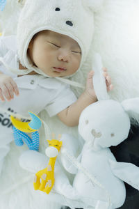 Cute baby boy sleeping with toy on bed at home