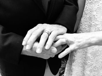 Midsection of bride and bridegroom holding hands during wedding ceremony