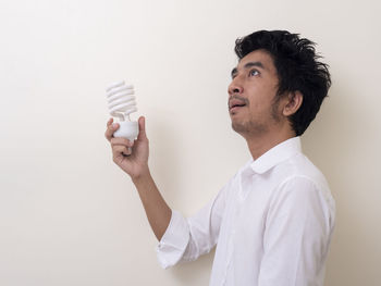 Portrait of young man looking away against white background