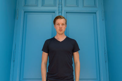 Portrait of man standing against blue door