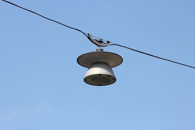 Low angle view of equipment hanging on cable against clear blue sky