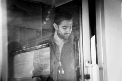 Close-up of young man looking through window