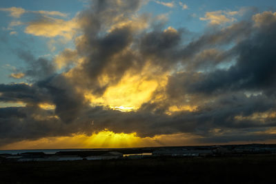 Scenic view of sea against dramatic sky during sunset