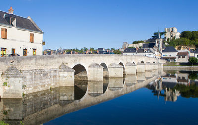 Arch bridge over river against buildings in city