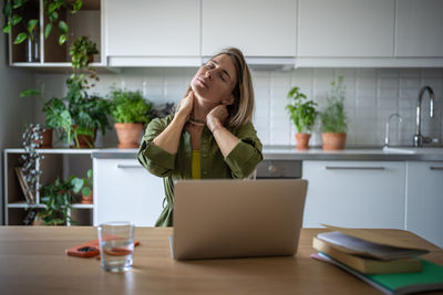 Overworked female relaxing, stretching muscles, massaging neck after work in uncomfortable position