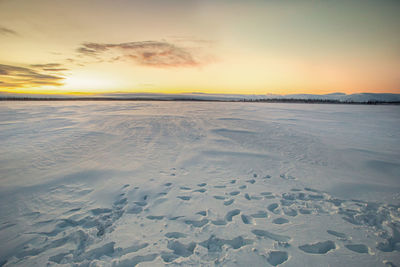 Scenic view of snow covered land during sunset