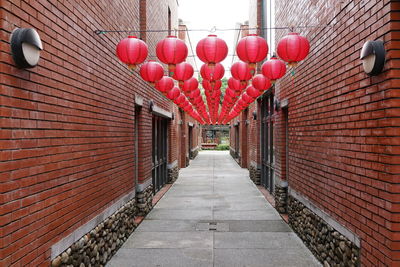 Red lanterns hanging on footpath amidst buildings