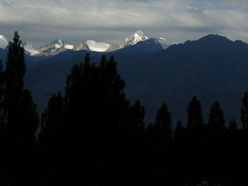 Silhouette trees and mountains against sky