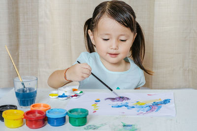 Cute girl painting on paper