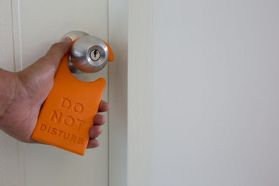 Cropped hand of woman holding do not disturb sign at door