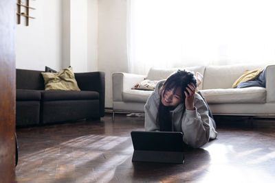 Smiling woman using tablet pc on floor in living room