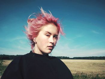 Portrait of beautiful young woman on field against sky