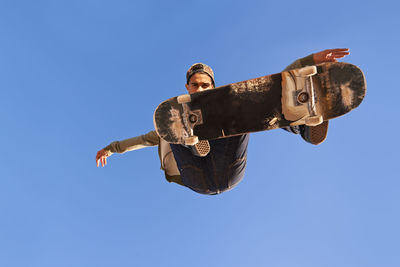 Low angle view of man jumping against clear sky