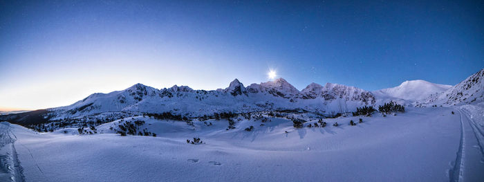 Scenic view of snowcapped mountains against clear blue sky at night