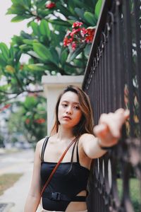 Portrait of young woman standing by gate