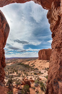 Landscape seen through hole in rock formations against sky