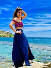 Portrait of woman standing at beach against sky