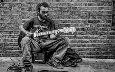 Man playing guitar against wall