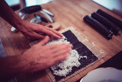 Cropped hands making sushi