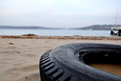 Abandoned tire at beach against sky