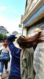 Low angle view of young woman against built structure