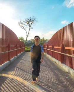 Full length portrait of young man standing on footbridge