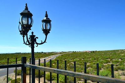 Street light on field against clear blue sky