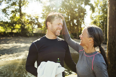 Happy woman pulling man's hair while standing by river
