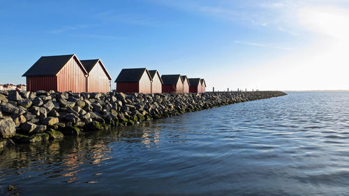 Stilt houses by sea against sky