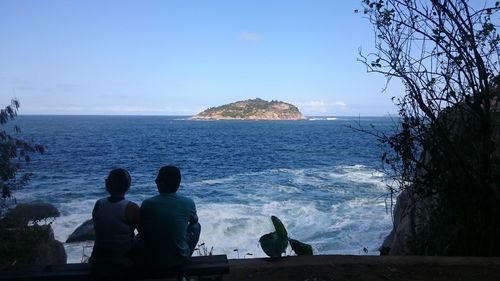 Rear view of people looking at sea against sky