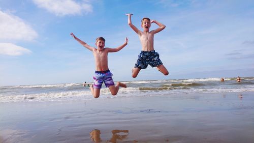 Full length of shirtless man jumping on beach