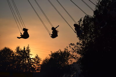 Low angle view of silhouette people sitting on against sky during sunset