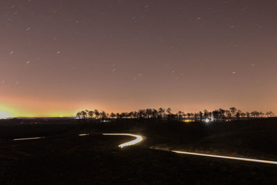 Light trails on road against sky at night