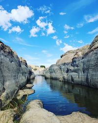 Rock formation by lake against sky