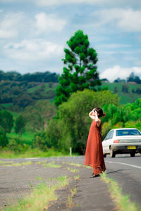 Young woman wearing sunglasses standing on road against trees in forest