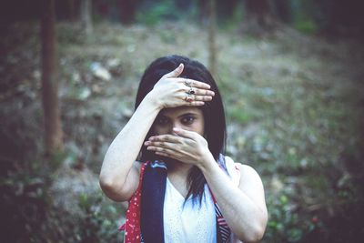 Portrait of young woman standing against blurred background