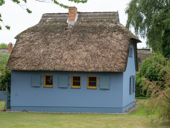 Exterior of house and trees on field against sky