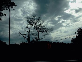 Low angle view of bare tree against cloudy sky