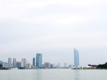 Sea and buildings in city against sky