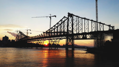 Suspension bridge over river against sky during sunset
