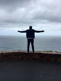 Rear view of man looking at sea against sky