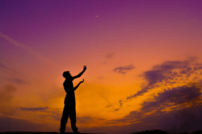 Silhouette man standing against orange sky