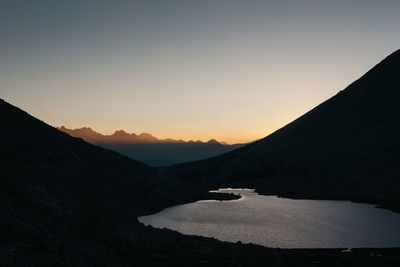 Scenic view of silhouette mountains against clear sky during sunset