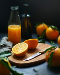 Close-up of orange by kitchen knife against juice on cutting board