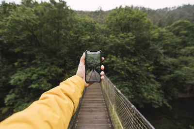 Rear view of man using mobile phone on footbridge