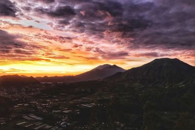 Scenic view of mountains against dramatic sky during sunset