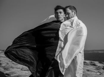 Gay men standing on land against sky